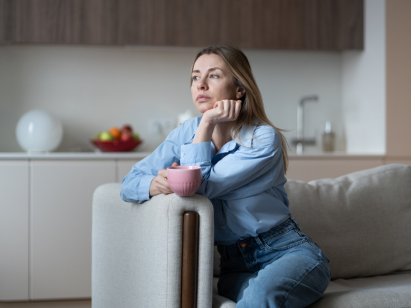 Slightly sad middle aged woman sitting on home couch looking bored