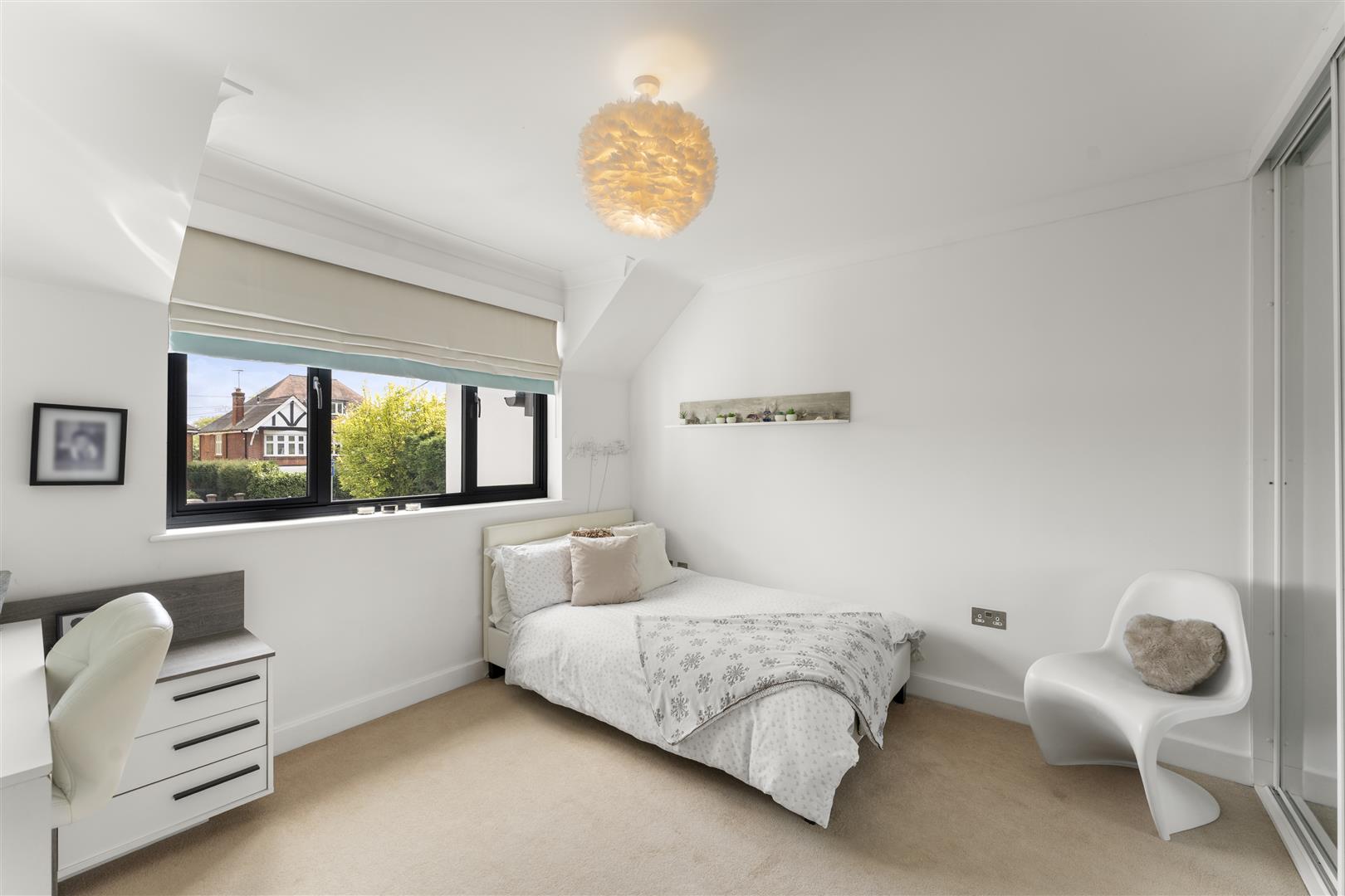 Bright minimalist bedroom with a large window, white walls, a bed with patterned white bedding, and a modern white chair.