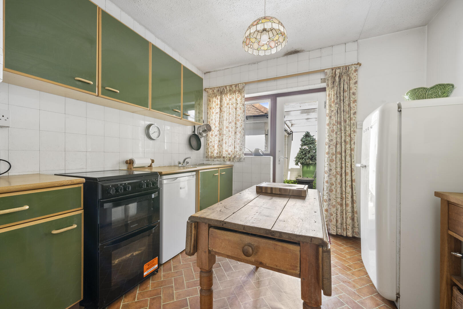 Retro-style kitchen with green upper cabinets, wooden drawers, and a rustic wooden table center stage.