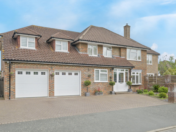Front view of a brick house with tiled roof, dormer windows, and a double garage.
