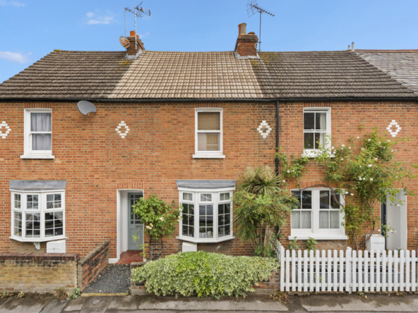 Red brick terraced house with white diamond decorative motifs, bay windows, and a small front garden.