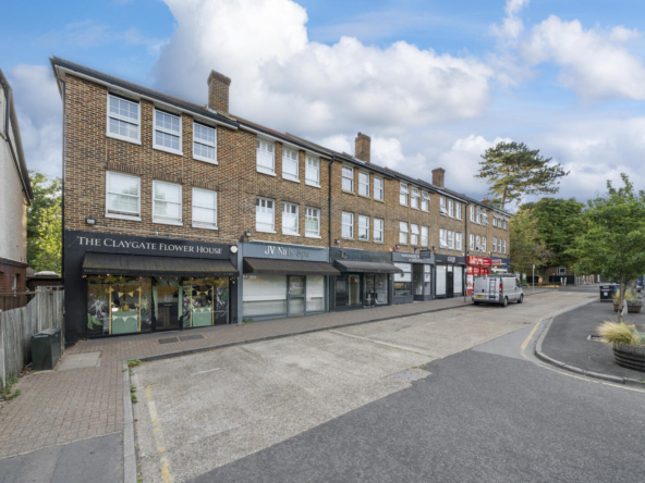 Row of brick storefronts along a quiet street, including The Claygate Flower House and JV Nails Spa under cloudy blue sky